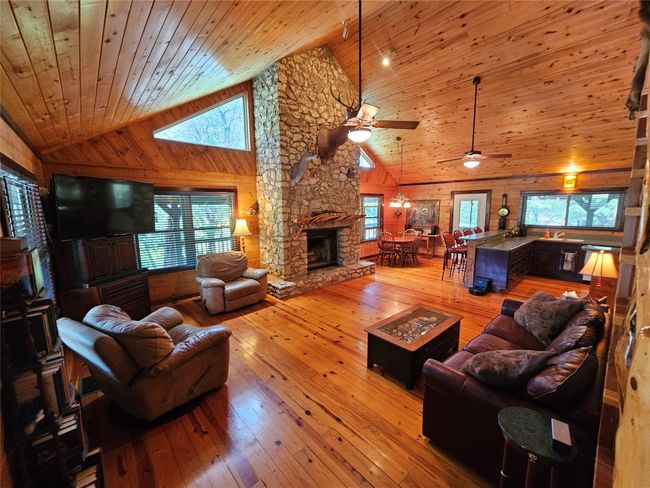 This is Stunning View upon entering the front door! - A Gorgeous Open Living area with a Massive stone fireplace, Large Windows, and Wooden Flooring, Walls and a High Vaulted Wooden Ceiling! | Image 6