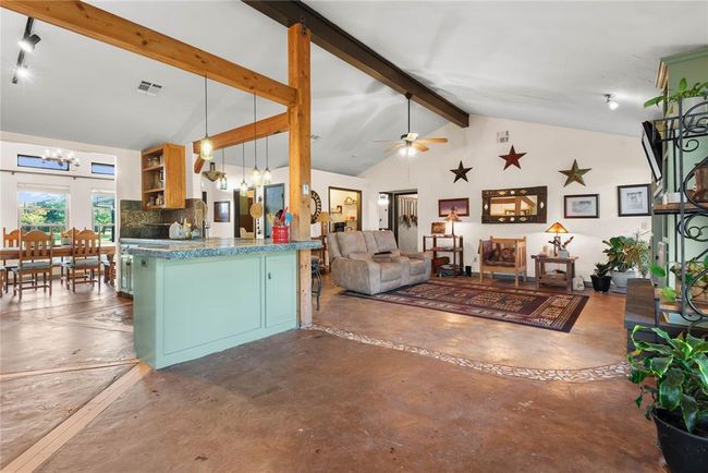 Kitchen featuring lofted ceiling with beams, open shelves, ceiling fan with notable chandelier, concrete flooring, and open floor plan | Image 11
