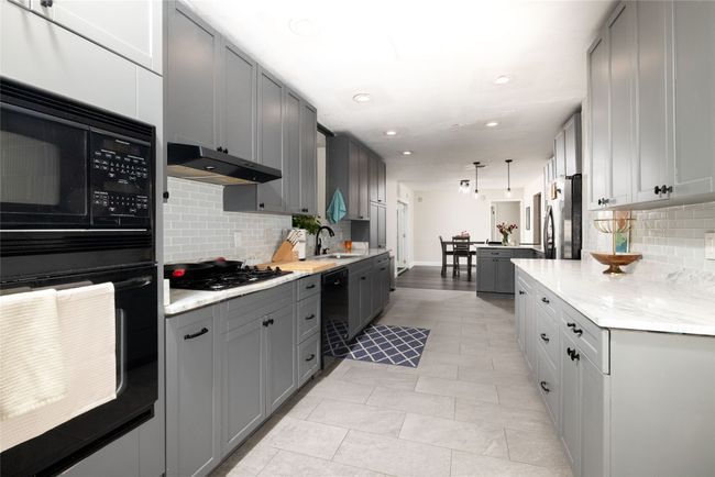 Kitchen featuring a sink, under cabinet range hood, black appliances, gray cabinets, and decorative backsplash | Image 17