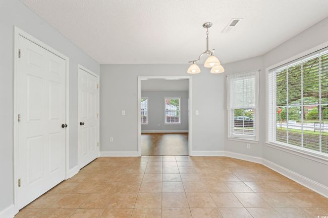 Unfurnished dining area with a chandelier, light tile patterned floors, and baseboards | Image 14