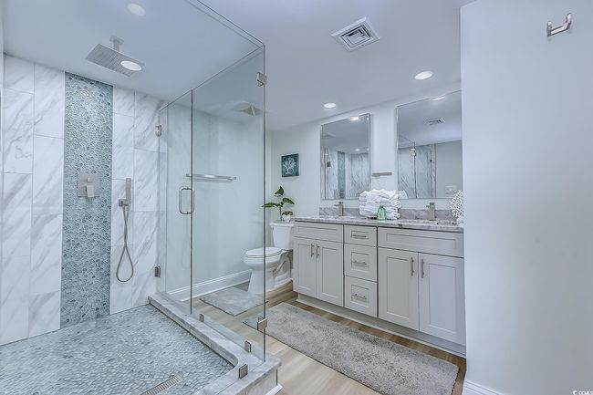 Bathroom featuring a shower with shower door, wood-type flooring, toilet, and vanity | Image 21