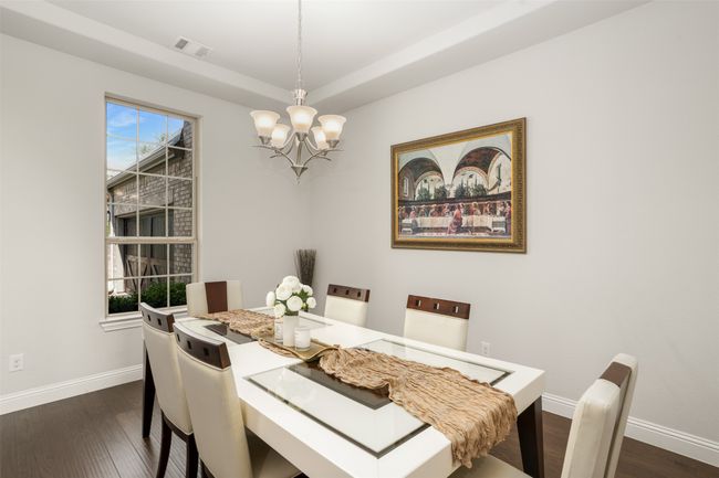 Dining area featuring a chandelier, visible vents, a raised ceiling, baseboards, and dark wood-style floors | Image 5