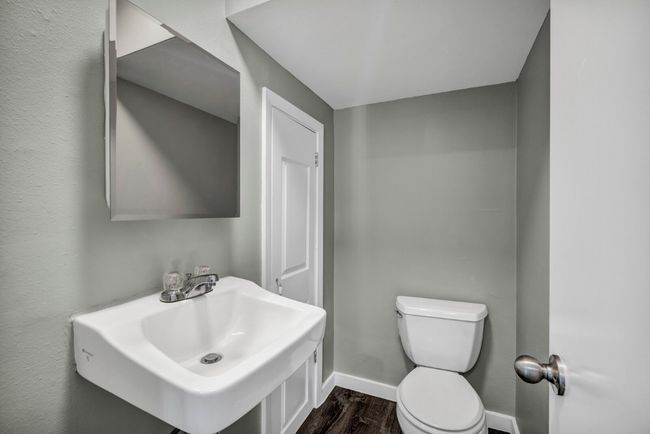 Bathroom featuring toilet, a sink, wood finished floors, and baseboards | Image 9