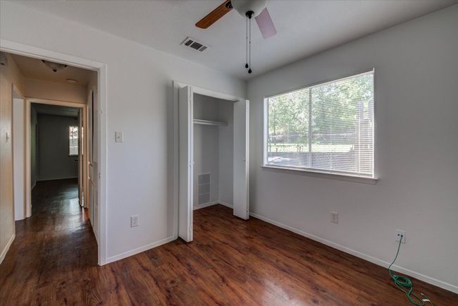 Unfurnished bedroom with visible vents, baseboards, a closet, and dark wood finished floors | Image 16