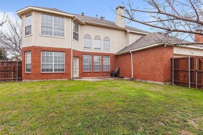Rear view of house featuring a fenced backyard, brick siding, a patio area, and a lawn | Image 26