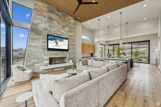 Living area with recessed lighting, a towering ceiling, a stone fireplace, wood ceiling, and light wood-style flooring | Image 21