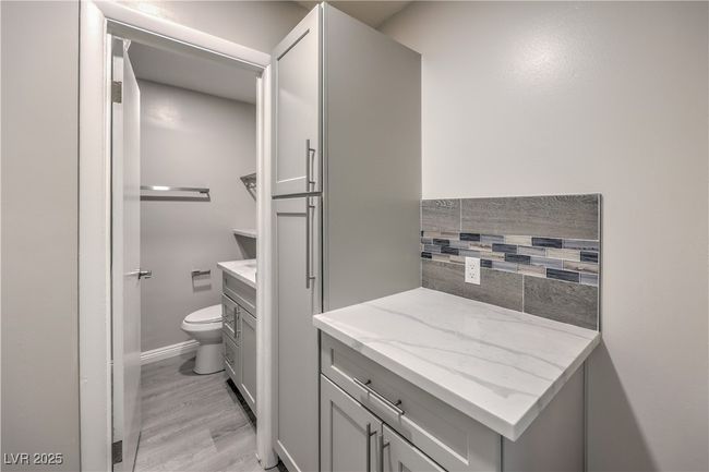 Bathroom featuring toilet, wood finished floors, vanity, baseboards, and backsplash | Image 33