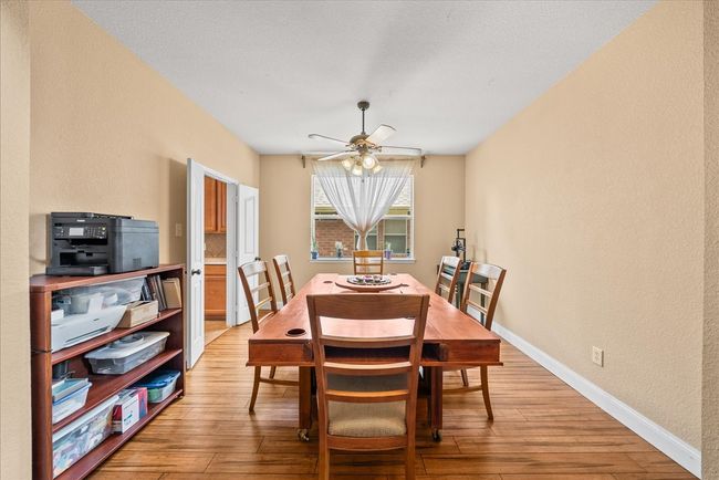 Dining area with light wood-style floors, baseboards, a ceiling fan, and a textured wall | Image 6