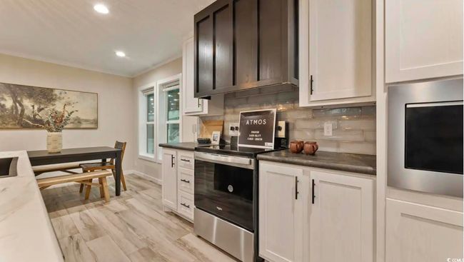 Kitchen with stainless steel appliances, tasteful backsplash, recessed lighting, light wood-style floors, and white cabinets | Image 13