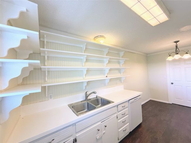 Kitchen featuring open shelves, dishwasher, white cabinetry, dark wood-style floors, and light countertops | Image 8