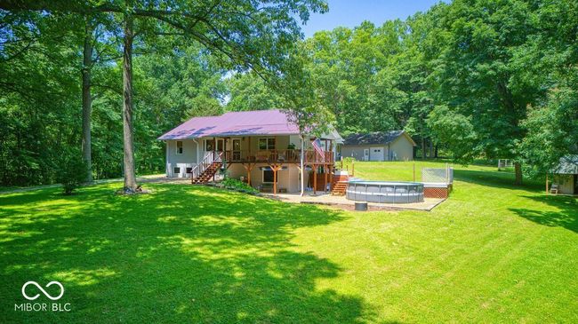 rear view of property with stairs, a lawn, a metal roof, a deck, and a patio | Image 7