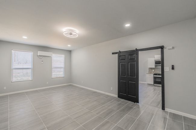 Spare room featuring a wall mounted AC, baseboards, a barn door, and recessed lighting | Image 8