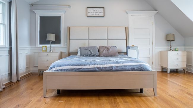 Bedroom with light wood finished floors, vaulted ceiling, and a wainscoted wall | Image 19