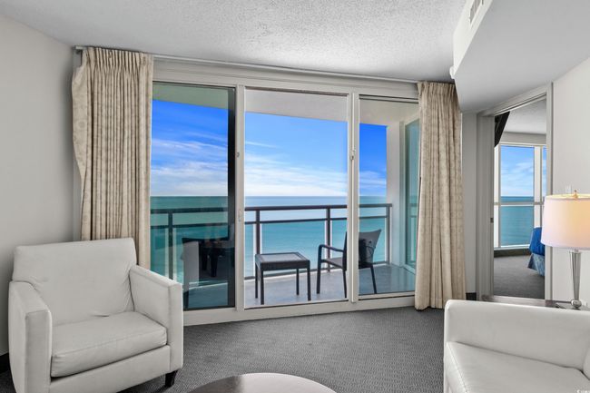 Living area with a water view, a textured ceiling, and carpet floors | Image 16
