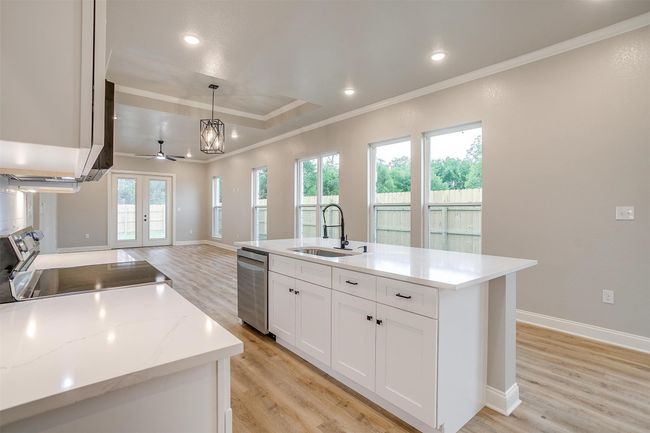Kitchen featuring crown molding, appliances with stainless steel finishes, a sink, white cabinets, and light wood-style floors | Image 13