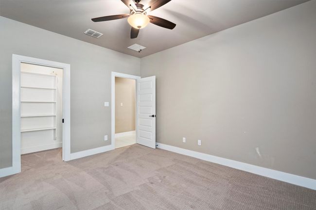 Unfurnished bedroom featuring light colored carpet, a spacious closet, and ceiling fan | Image 21