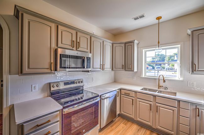 Kitchen featuring appliances with stainless steel finishes, light countertops, hanging light fixtures, and tasteful backsplash | Image 28