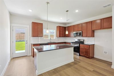 Kitchen featuring sink, a kitchen island, light hardwood / wood-style flooring, stainless steel appliances, and dark stone counters | Image 3