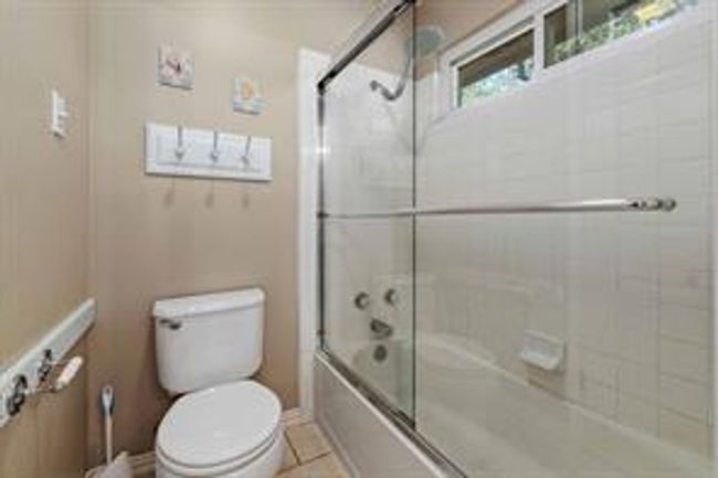 Bathroom featuring tile patterned flooring, toilet, and bath / shower combo with glass door | Image 32