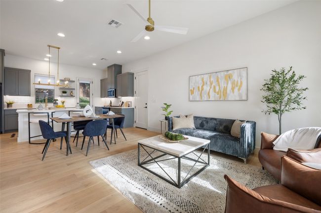 Living area with light wood-type flooring, visible vents, recessed lighting, and ceiling fan with notable chandelier | Image 4