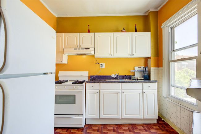 Kitchen featuring white appliances, under cabinet range hood, white cabinets, and ornamental molding | Image 31