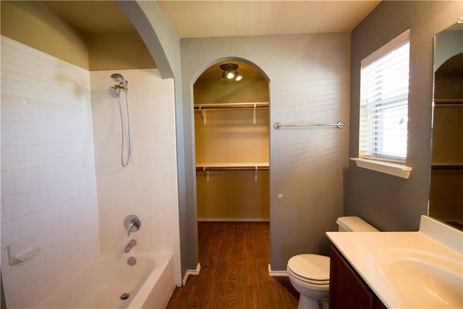 Bathroom featuring wood finished floors, vanity, shower / bath combination, and a spacious closet | Image 5