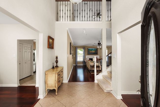 Foyer entrance featuring light tile patterned floors, a high ceiling, a ceiling fan, stairs, and washer / dryer | Image 7