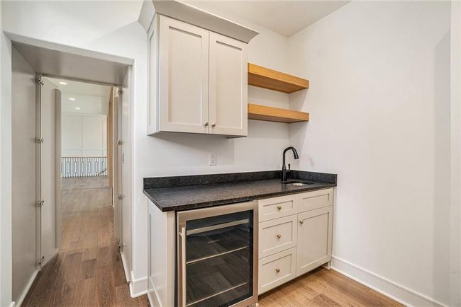 Indoor bar with beverage cooler, light wood-style floors, and baseboards | Image 30
