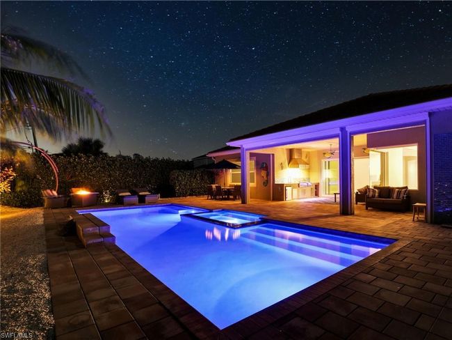 Pool at night featuring outdoor lounge area, an in ground hot tub, and a patio | Image 41