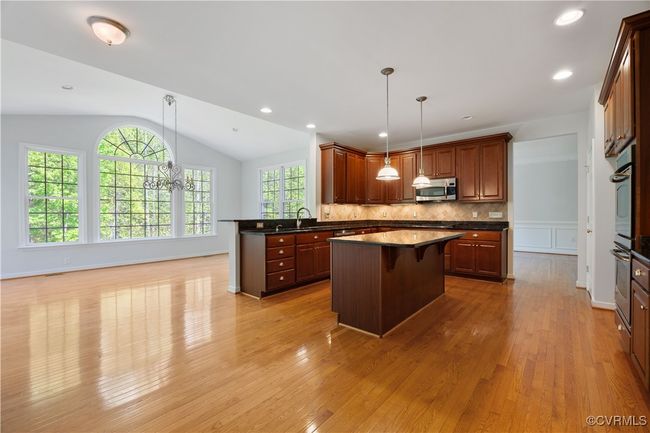 Kitchen with stainless steel microwave, a healthy amount of sunlight, a center island, dark countertops, and lofted ceiling, morning room with bar top | Image 16