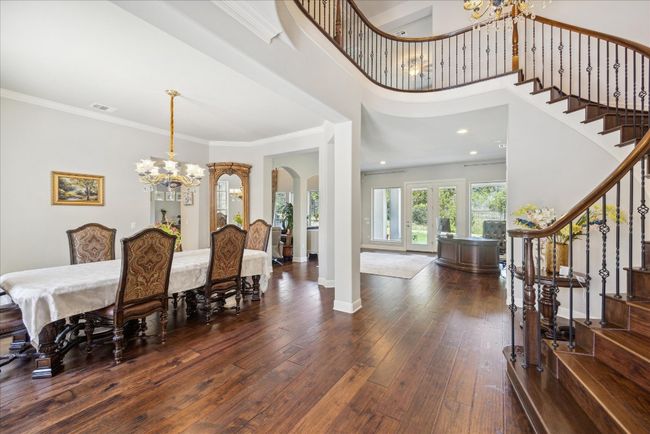 Dining room with stairs, an inviting chandelier, wood-type flooring, ornamental molding, and arched walkways | Image 7