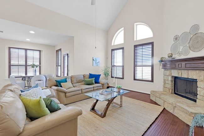 Living area featuring plenty of natural light, high vaulted ceiling, wood finished floors, and a fireplace | Image 8