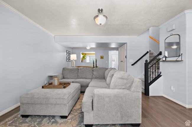 Living room with stairs, crown molding, wood finished floors, and a textured ceiling | Image 5