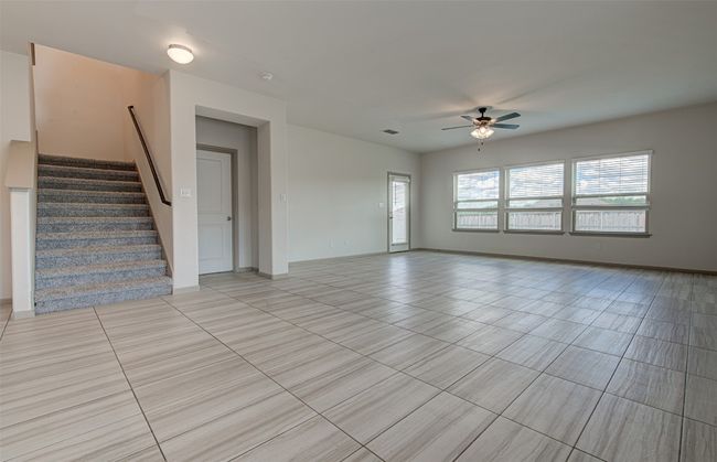 Unfurnished living room featuring ceiling fan, light tile patterned floors, stairway, and baseboards | Image 14