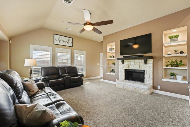 Carpeted living area with built in shelves, ceiling fan, baseboards, and visible vents | Image 15