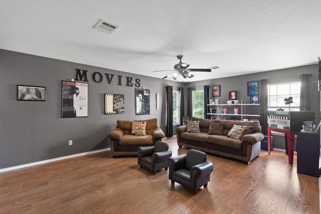 Living room with a textured ceiling, wood finished floors, visible vents, and a ceiling fan | Image 31