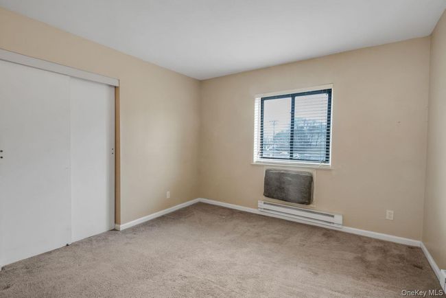 Unfurnished bedroom with baseboard heating, a closet, baseboards, and carpet floors | Image 20