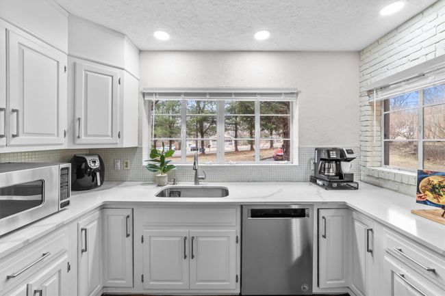 Kitchen with a sink, quartz countertops, appliances with stainless steel finishes, white cabinetry, and tasteful backsplash | Image 12