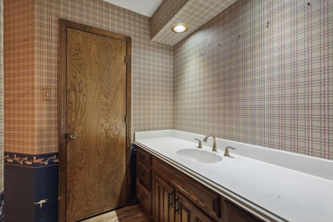 Bathroom with wallpapered walls, wood finished floors, and vanity | Image 28