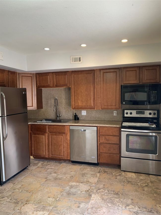 Kitchen featuring fridge, dishwasher, stove, a sink, and decorative backsplash | Image 9