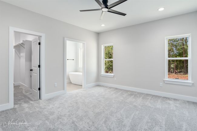 Unfurnished bedroom featuring a walk in closet, carpet flooring, baseboards, and multiple windows | Image 13