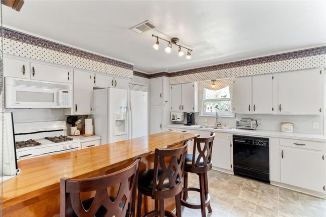 Functional (13x12) kitchen with plentiful cabinet & storage space, a gas range for cooking enthusiasts & a spacious breakfast bar perfect for quick meals or additional seating. | Image 7