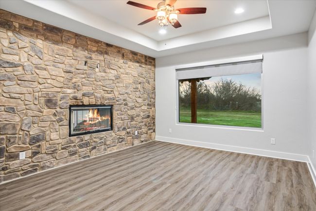Unfurnished living room with hardwood / wood-style floors, ceiling fan, a fireplace, and a tray ceiling | Image 15