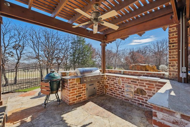 The outdoor kitchen as a built in grill, 2 refrigerators, and bar seating for up to 15 people. | Image 33