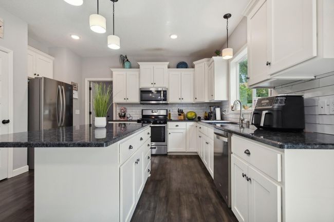 Kitchen boasts granite counters, hardwood floors, and stainless appliances. | Image 5