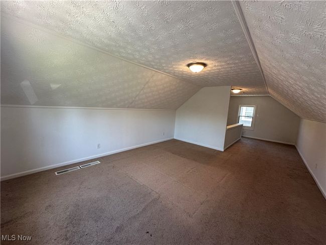Bonus room featuring visible vents, carpet, baseboards, a textured ceiling, and lofted ceiling | Image 28