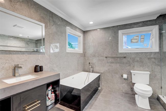 Bathroom featuring tile walls, toilet, vanity, a garden tub, and crown molding | Image 17