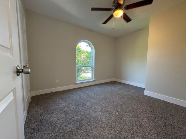 Unfurnished room featuring ceiling fan, dark colored carpet, and baseboards | Image 16