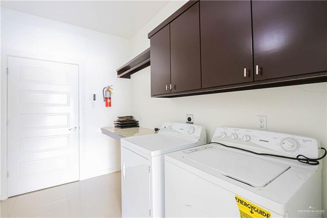 Clothes washing area with cabinet space, washing machine and clothes dryer, and light tile patterned floors | Image 11