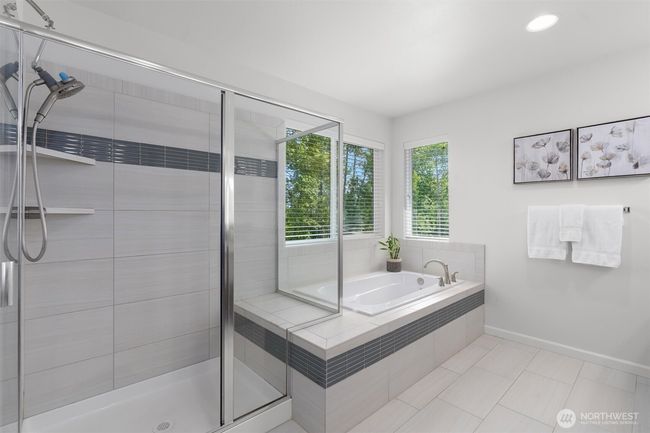 Unwind in the spa-inspired elegance of this luxurious primary bathroom, featuring a large soaking tub with tranquil tree-lined river views and a separate glass-enclosed walk-in shower. Sleek tile-work, modern fixtures, and abundant natural light create a serene and sophisticated retreat! | Image 22